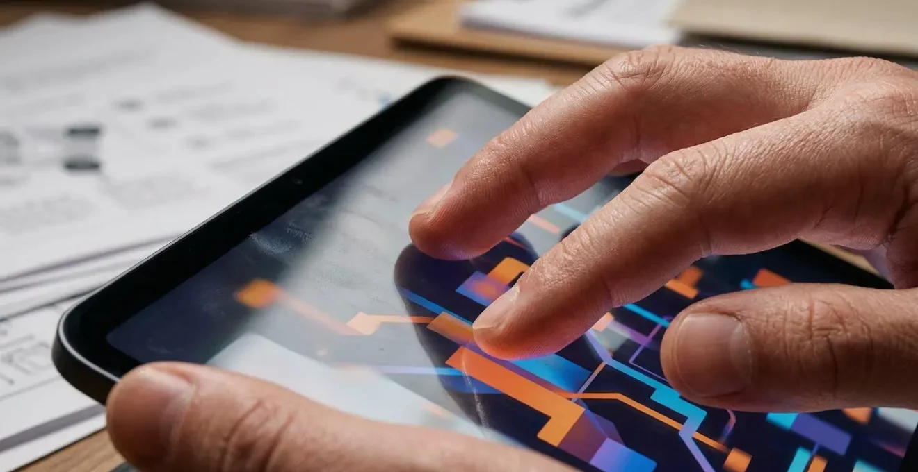 Vue macro de mains manipulant tablette avec interface interactive floue et documents papier en arrière-plan